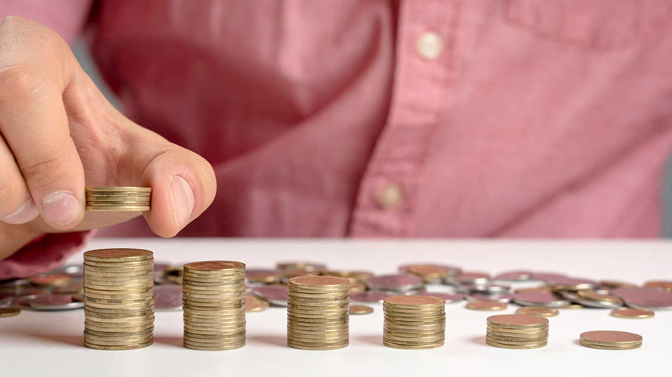 An individual stacks coins, representing saving and wealth-building.